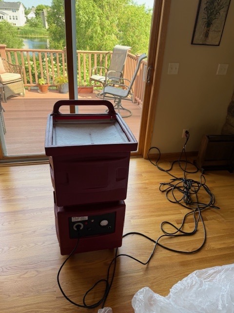Professional red dehumidifier unit positioned near sliding door for residential water damage restoration