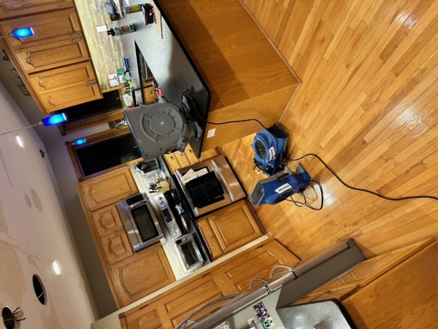 Complete kitchen water damage restoration setup with multiple air movers and professional drying equipment
